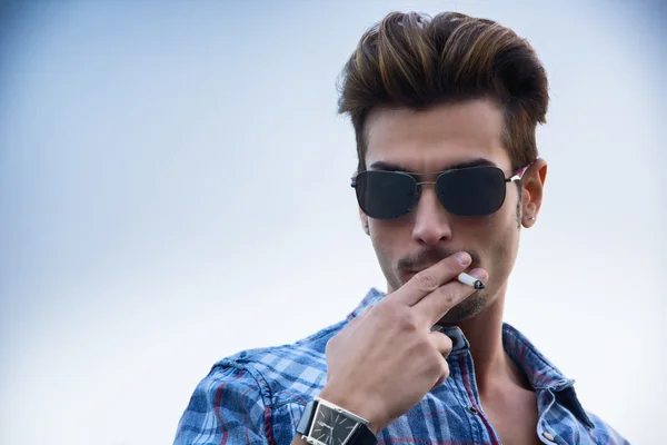 Young man standing outside smoking — Stock Photo, Image