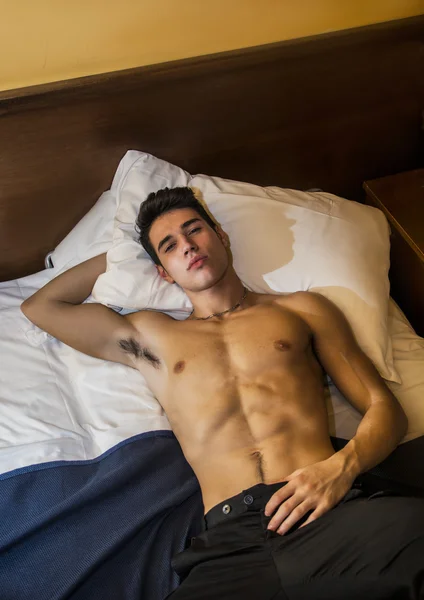 Gömleksiz atletik genç adam yatakta döşeme — Stok fotoğraf