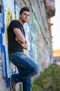 Çekici genç adam renkli grafiti duvara karşı ayakta