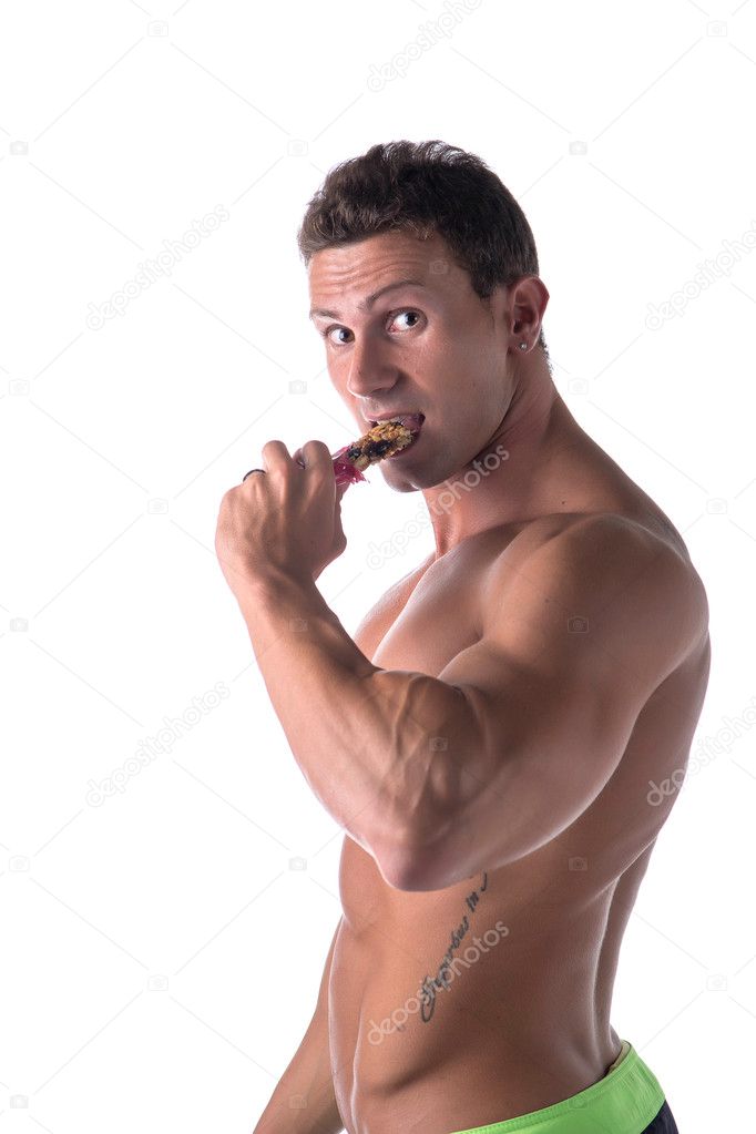 Shirtless muscular young man eating cereal bar