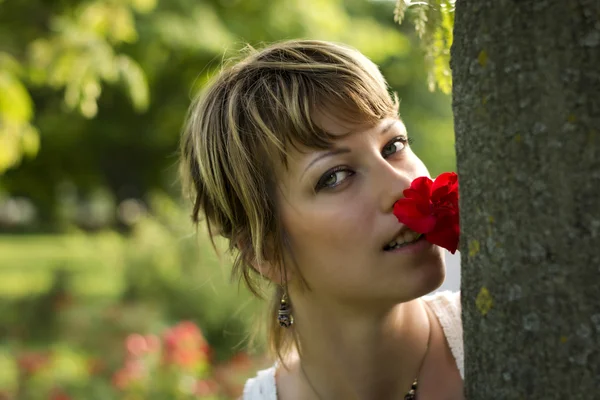 Mulher jovem e atraente no jardim ou parque com rosa vermelha — Fotografia de Stock