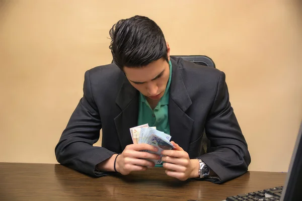 現金を手元に数える若いビジネスマンに座る — ストック写真