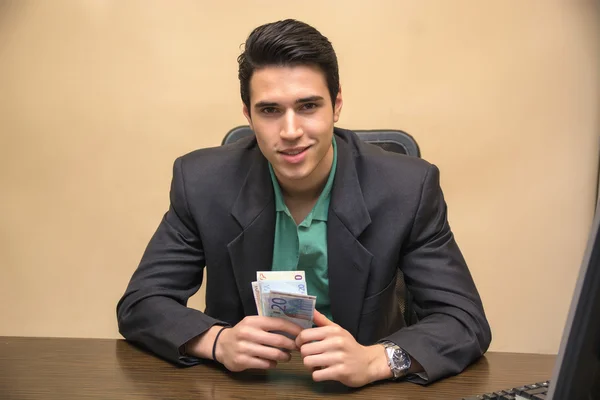 Junge Unternehmer, sitzt an seinem Arbeitstisch, zählen Bargeld zur Hand — Stockfoto