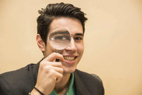 Handsome young man holding a magnifying glass — Stock Photo, Image