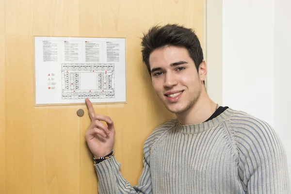 Jovem em hotel apontando para a planta da feira — Fotografia de Stock