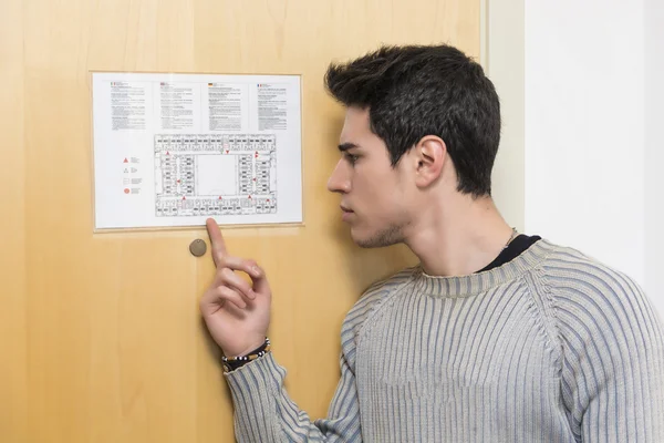 Young man in hotel pointing at floorplan — Stock Photo, Image