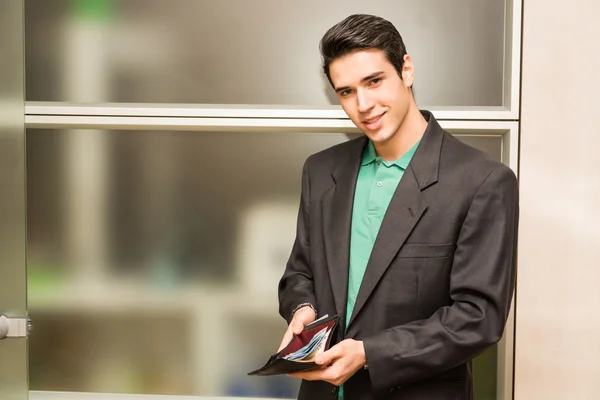 Young business man in office showing full wallet — Stock Photo, Image