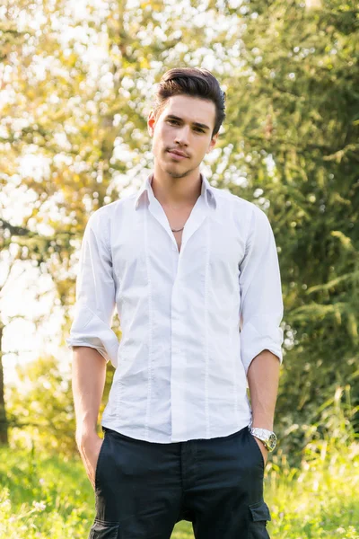 Attractive young man standing in a forest – stockfoto