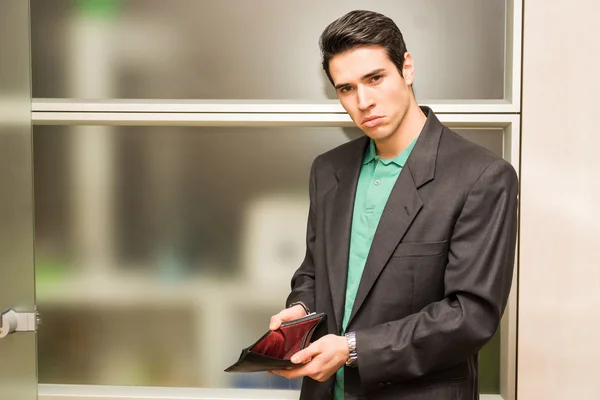 Sad looking young man showing empty wallet — Stock Photo, Image