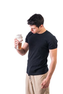 Çekici bir genç adam protein içeceği şişesini tutuyor.