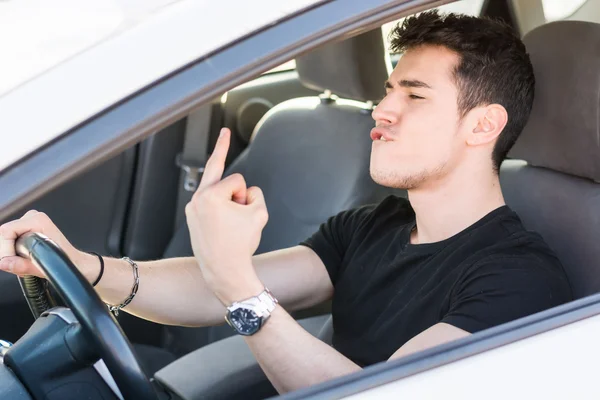 Hombre conduciendo un coche y mostrando el dedo medio — Foto de Stock