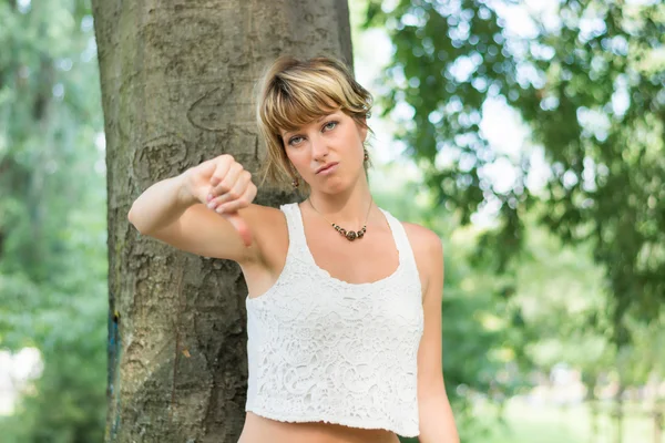 Blonde jonge vrouw buiten doen duim omlaag teken — Stockfoto