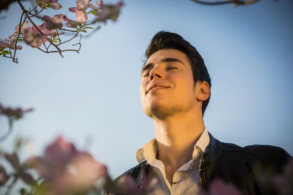 Good looking male model at couuntryside, among flowers — Stock Photo, Image