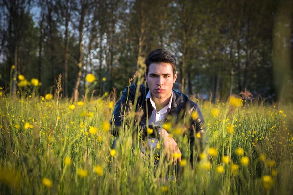 Knappe, sexy man buiten in de tuin crouching neer op gras — Stockfoto