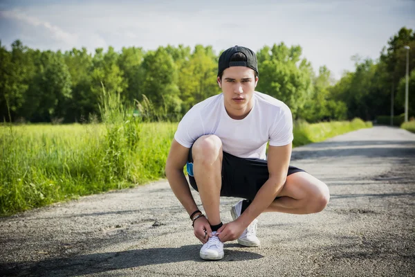 Knappe jongeman koppelverkoop sportschoenen voordat u gaat — Stockfoto