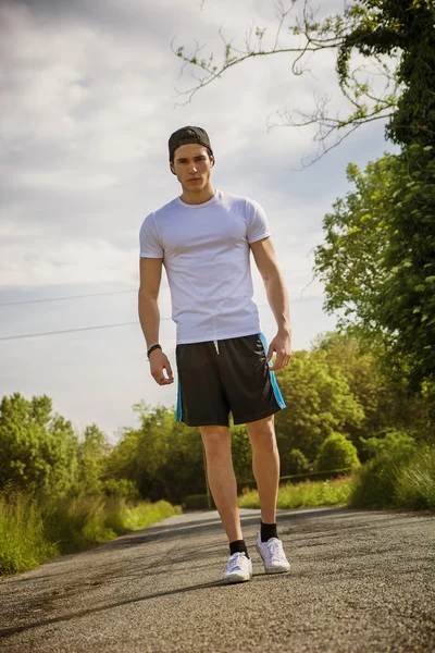 Handsome young man walking and trekking on road — Stock Photo, Image