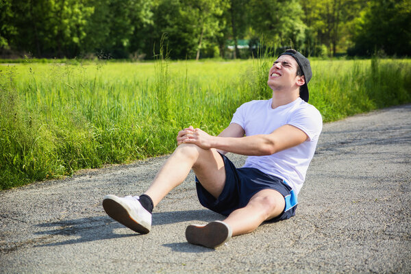 Handsome young man injured while running and jogging on road