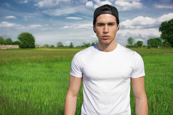 Handsome passar ung man på landsbygden, klädd i vit t-shirt — Stockfoto