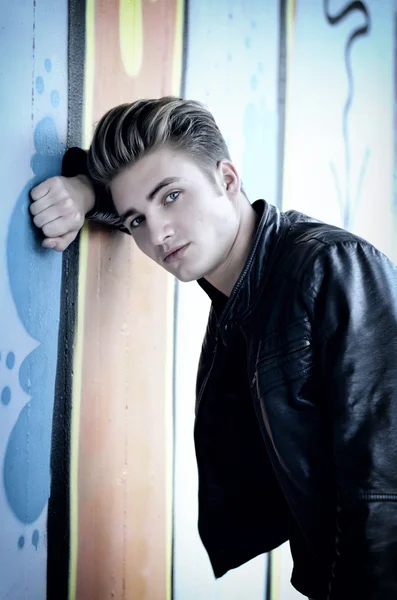 Blond young man leaning against graffiti wall — Stock Photo, Image