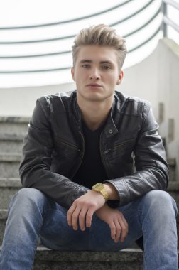 Merdivenlerde oturan sarışın genç adam