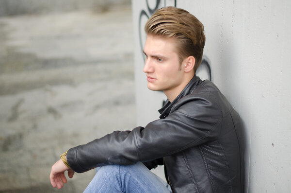 Blond young man sitting on stairs outside