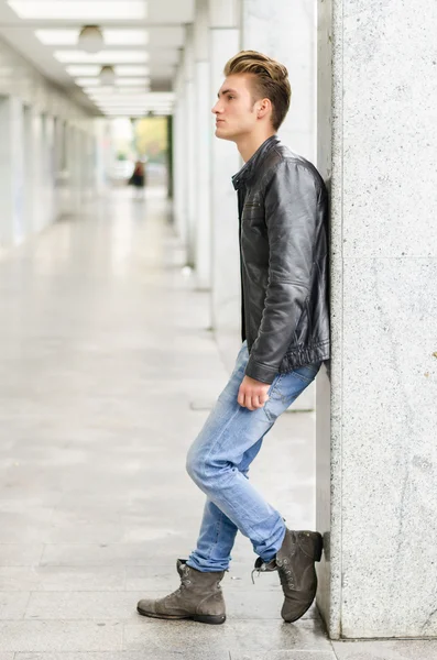 Young man standing outside against pillar — Stock Photo, Image