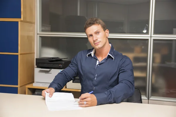 Young man doing paperwork at office desk — Stock Photo, Image