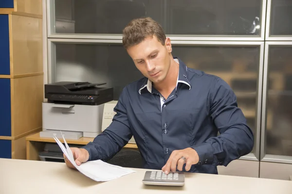 Красивый мужской офисный работник, используя калькулятор — стоковое фото