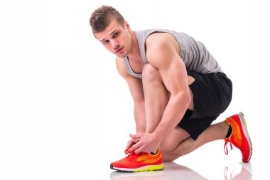 Yakışıklı genç bir adam diz çökmüş ve uygulamakla spor ayakkabı