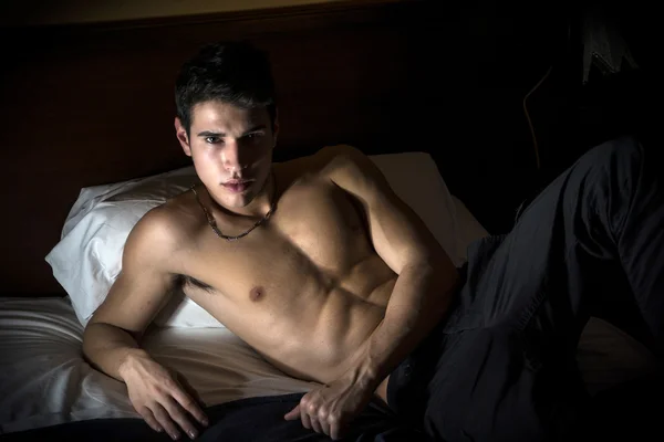 Shirtless athletic young man laying in bed — Stock Photo, Image
