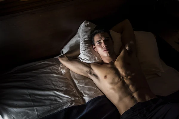 Shirtless athletic young man laying in bed — Stock Photo, Image