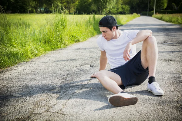 Hombre sentado descanso en el camino después de correr — Foto de Stock
