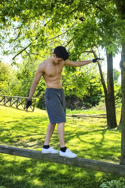 Jovem sem camisa balanceamento na barra de madeira — Fotografia de Stock