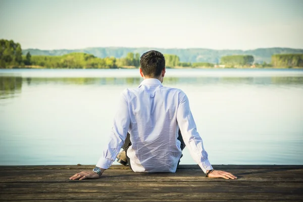 Schöner junger Mann am See in einem sonnigen — Stockfoto