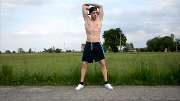 Молодой человек на открытом воздухе делает упражнения на растяжку — стоковое видео