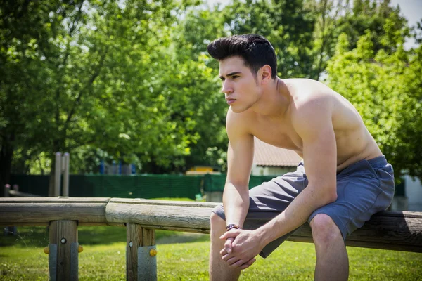 Молодой человек отдыхает в городском парке, сидя — стоковое фото