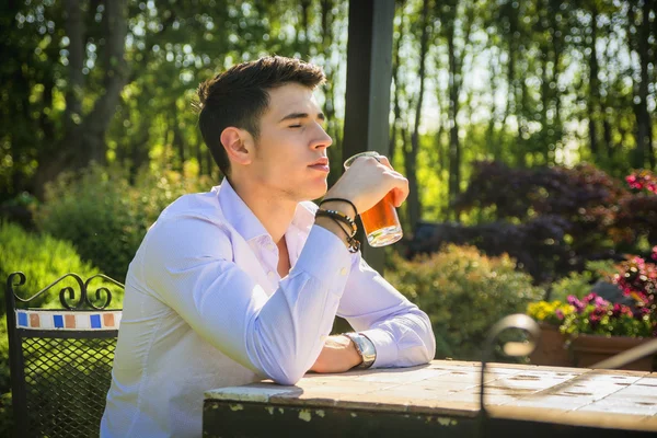 Man sitting alone at table outside in park — Stock Photo, Image