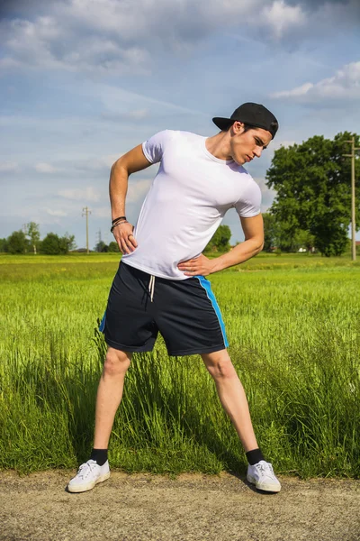 Jonge man buiten in land doet zich het uitrekken — Stockfoto