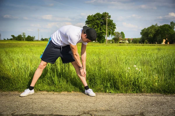 Giovane all'aperto in paese facendo stretching — Foto Stock