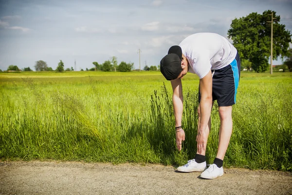 Joven al aire libre en el país haciendo estiramientos —  Fotos de Stock