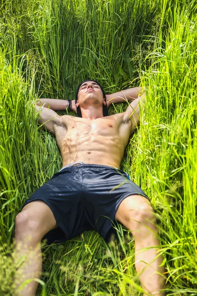 Jóvenes sin camisa musculares hombre relax tumbado en un campo —  Fotos de Stock