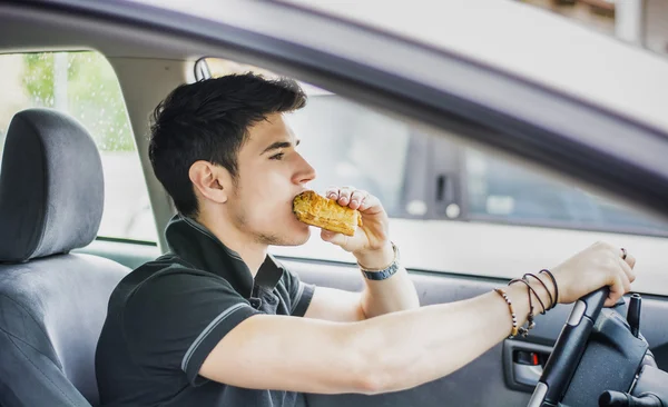 Hombre conduciendo su coche al comer alimentos — Foto de Stock