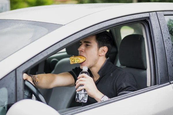 Человек, за рулем своего автомобиля во время приема пищи — стоковое фото