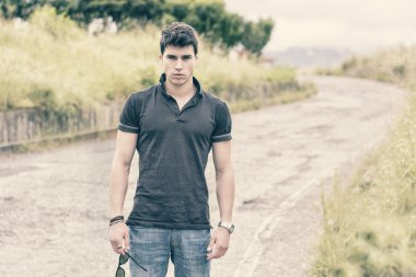 kot pantolon ve siyah tişört kırsal yolda yürüyen genç adam
