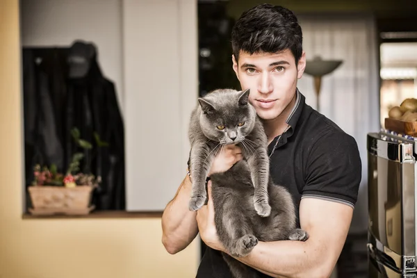 Guapo joven abrazando a su mascota gato gris —  Fotos de Stock
