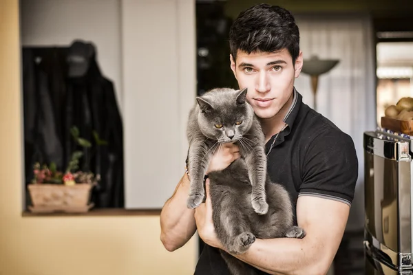 Jovem bonito abraçando seu animal de estimação gato cinza — Fotografia de Stock