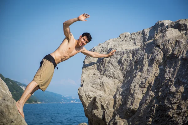 Young Man Spanning Gap Between Coastal Boulders — Stock Photo, Image