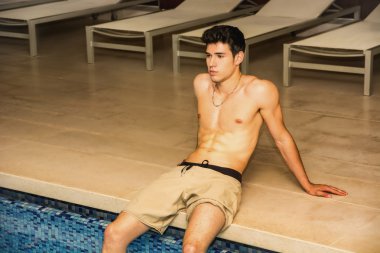 muhteşem gömleksiz genç adam havuz üzerinde oturur