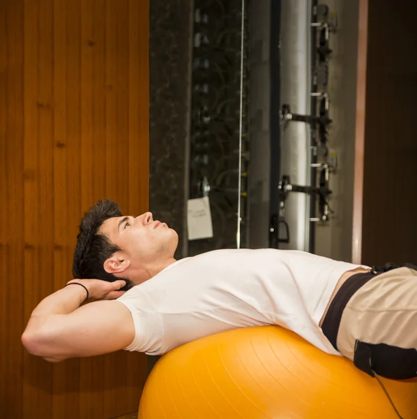 Junger Mann trainiert Bauchmuskeln auf Fitnessball — Stockfoto