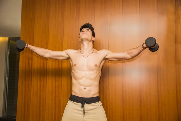 Attractive young man working out with dumbbells at gym — Stock Photo, Image